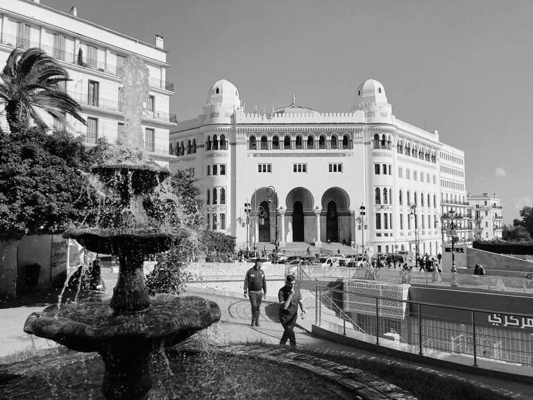 Black and white view of a historic building and fountain in Algiers.